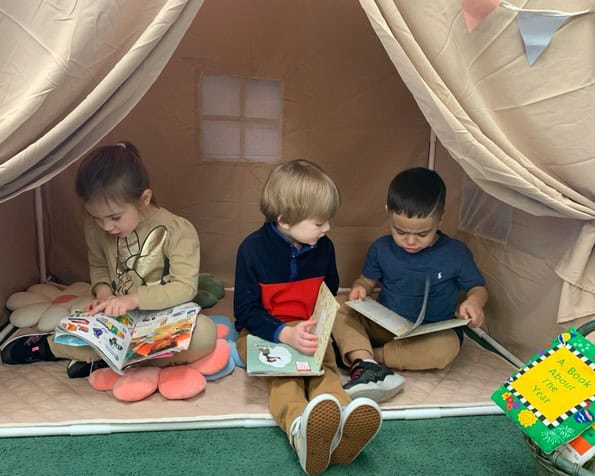 Children reading books inside a play tent at Trinity Episcopal Preschool.
