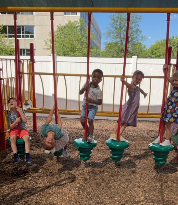 Children playing on playground equipment at Trinity Episcopal Preschool, showcasing a safe and engaging outdoor environment for early childhood development.