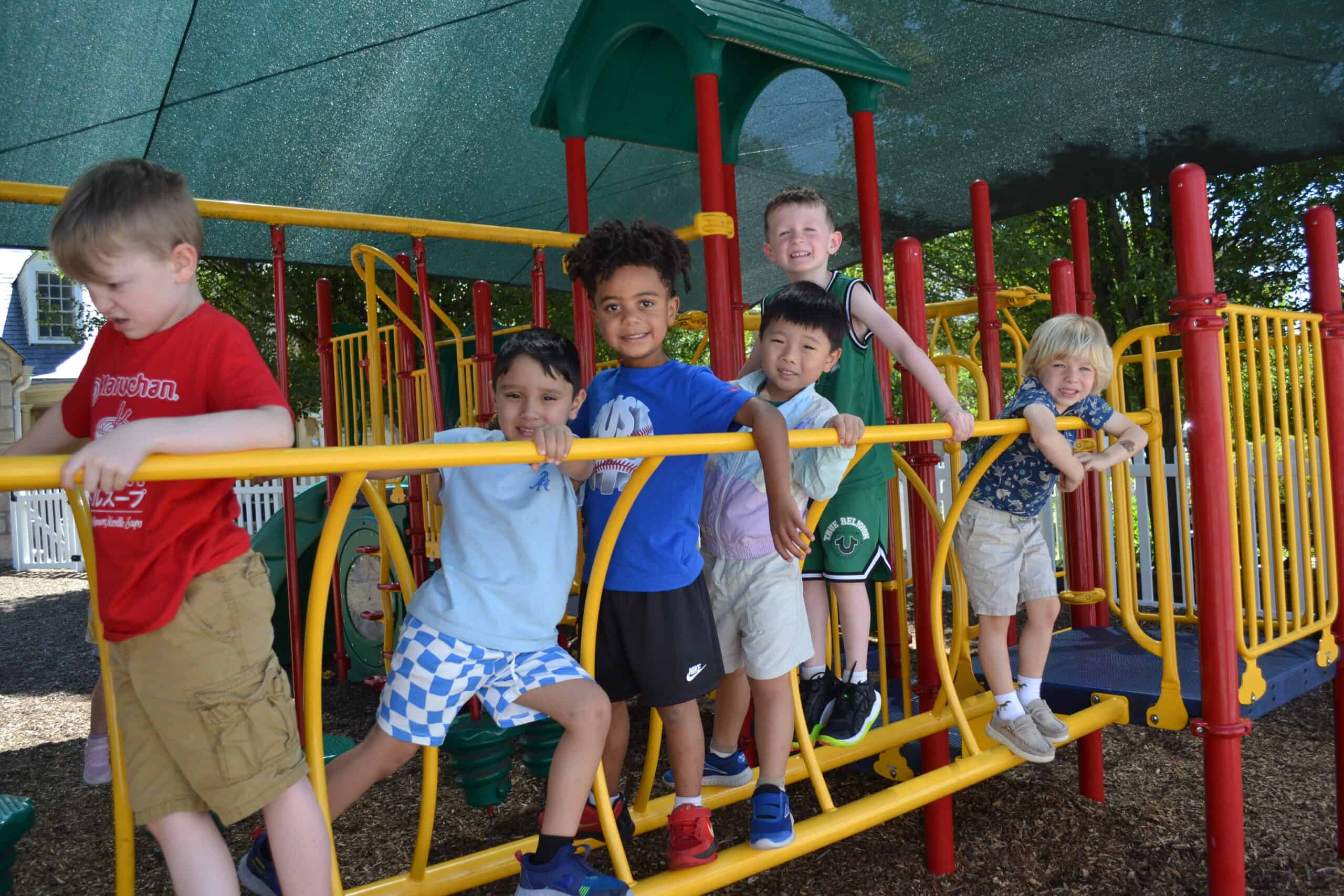 Group of happy preschool children playing on colorful outdoor playground equipment at Trinity Episcopal Preschool, enjoying outdoor activities and socializing.