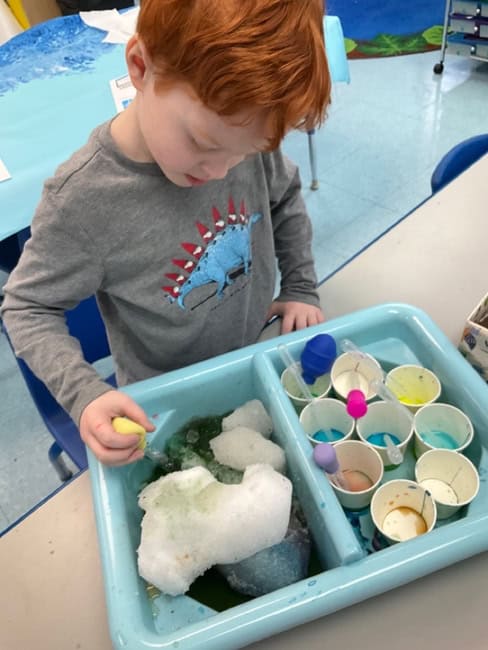 Young child exploring science with colorful cups and foam at Trinity Episcopal Preschool, fostering early learning and curiosity in a safe, nurturing environment.
