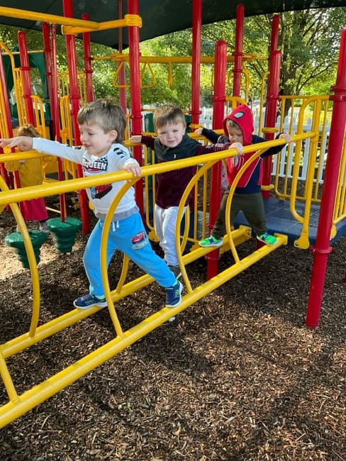 Young children playing on colorful playground structure at Trinity Episcopal Preschool, engaging in outdoor activities and developing social skills in a safe, supervised environment.
