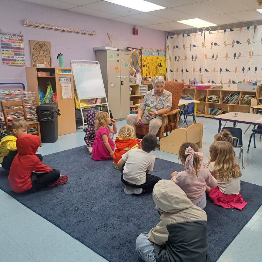 Preschool teacher reading to young children in a colorful classroom at Trinity Episcopal Preschool.