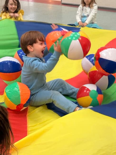 Young children playing with colorful beach balls on an inflatable bounce house at Trinity Episcopal Preschool, promoting fun, learning, and early childhood development.