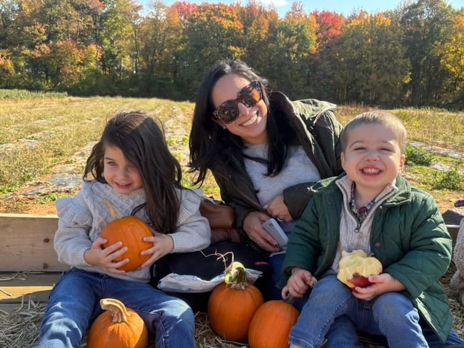 Happy children and teacher enjoying outdoor fall activities at Trinity Episcopal Preschool, surrounded by colorful autumn trees and pumpkins.
